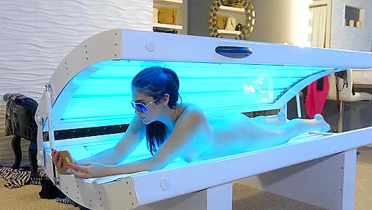 Young woman lies in tanning bed and enjoys XXX masturbation on her own